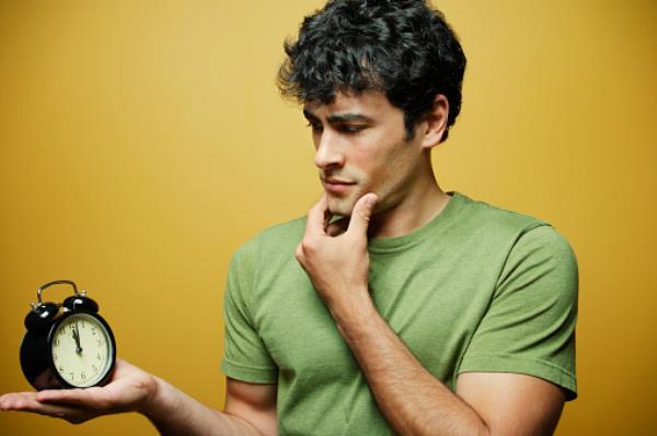 Man looking at clock in confusion